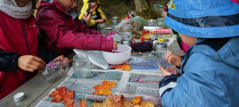 Barn rundt en utebenk limer perler og blader på Norgesglass.