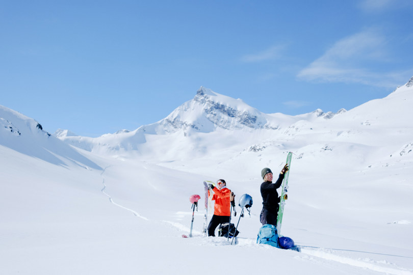 To mennesker tar på feller på ski i vinterlandskap.