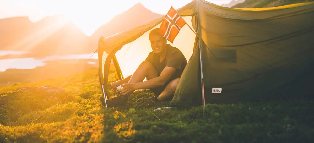 Mann i teltåpning i solnedgang