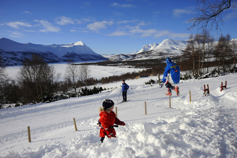 barn leker i snøen med fjellandskap i bakgrunnen