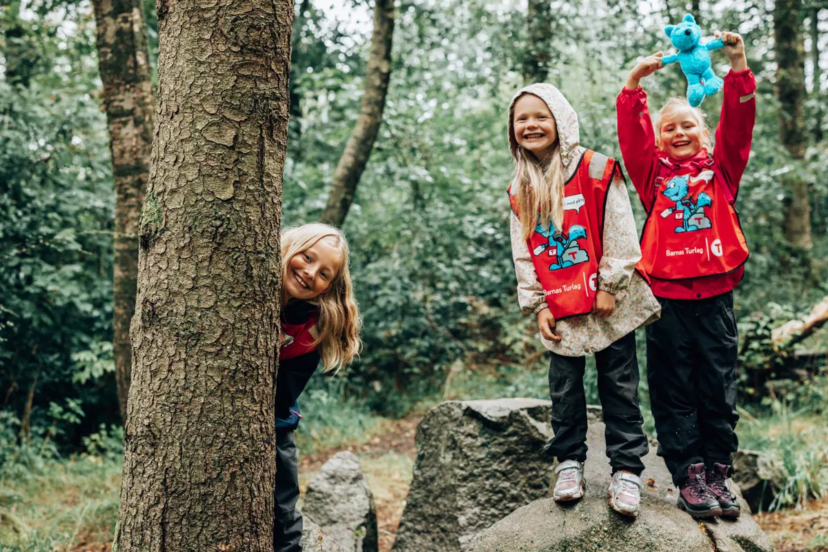 Tre glade barn i skogen.