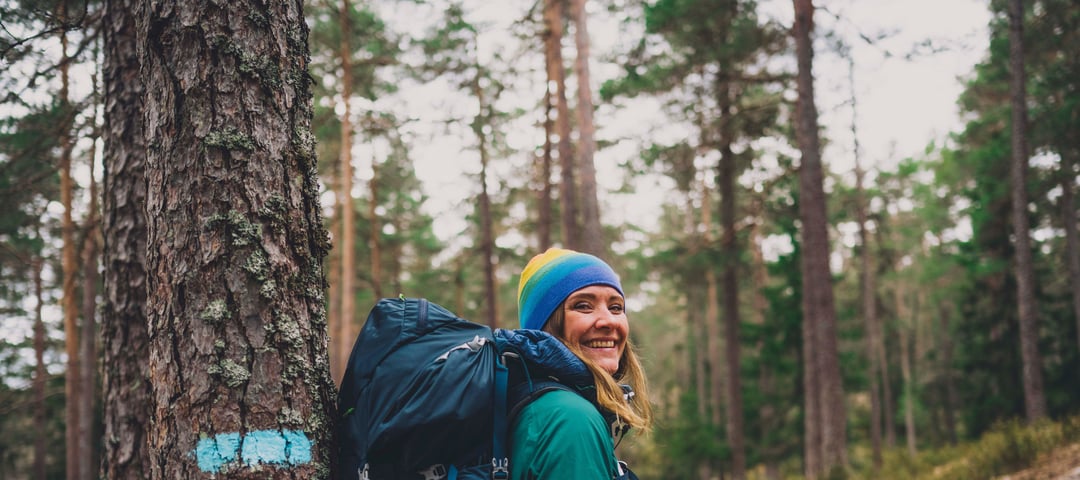Kvinne med stor sekk i skogen