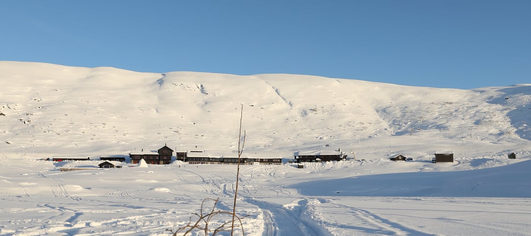 Haukeliseter Fjellstue. Det er en god del snø og solen skinner. Det er sccoterspor da de setter opp kvist. 