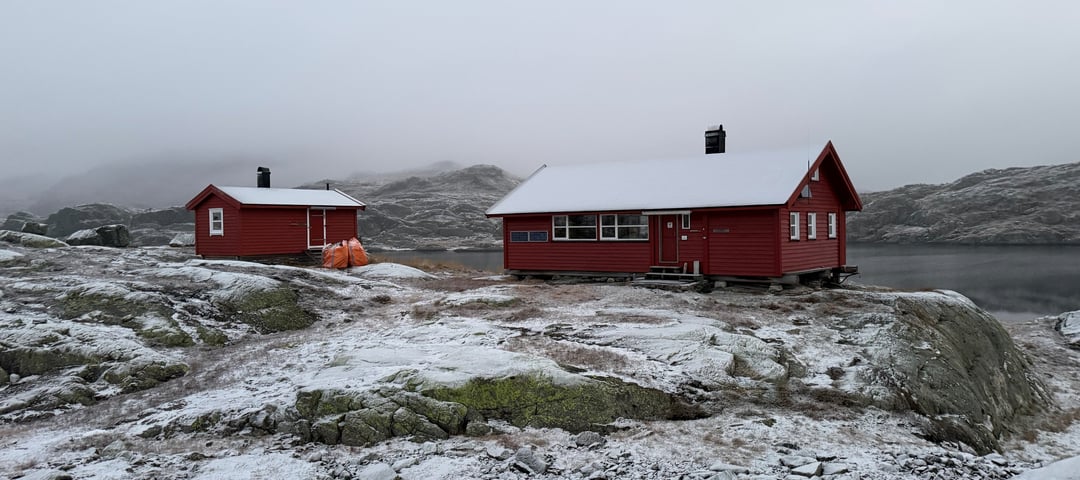 Krossvatn. 2 røde hytter. Det er litt snø på bakken og viser at vinteren nærmer seg.
