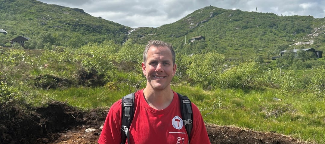 Mann i rød t-skjorte står i naturen