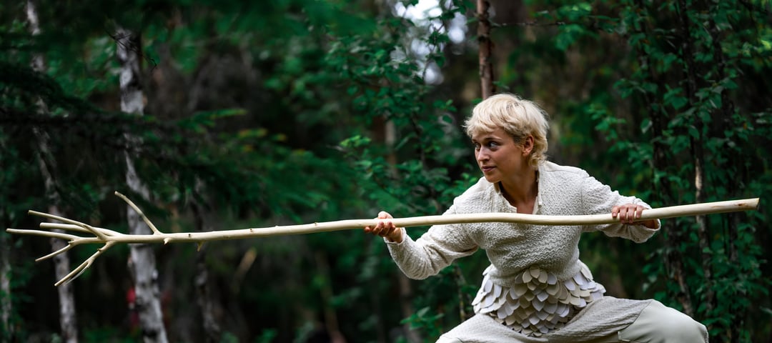 Danser i hvit drakt og lang kost i hånda