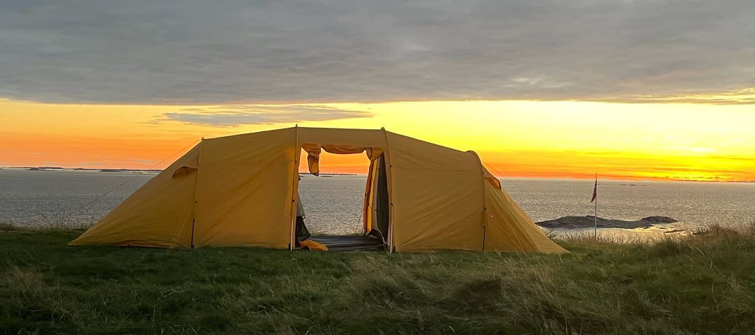 Bilde av et gult telt i solnedgangen.