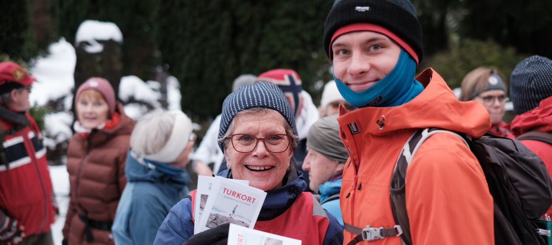 Kvinne og mann står med turklær på og viser frem et kort. 
