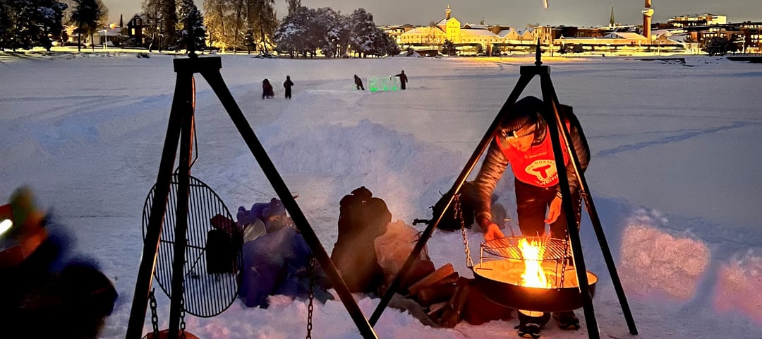 Mann fyrer opp i bålpanne på vinteren.