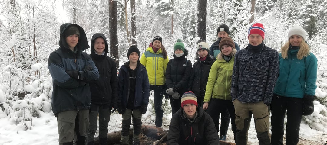 Blide ungdommer samlet rundt bålet.