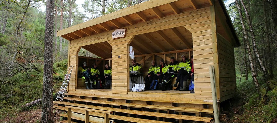 Trivselsgruppa i gule arbeidsklede inne i Drangebu gapahuk 