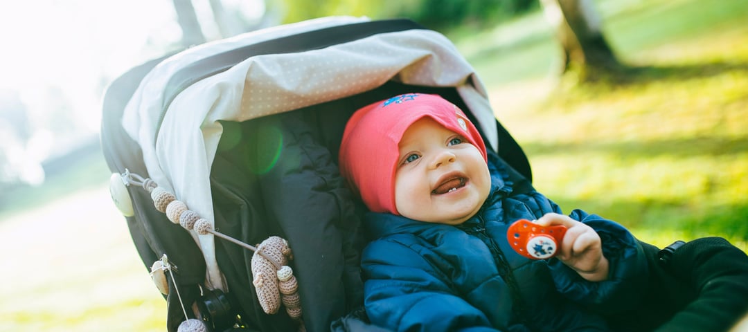 Spedbarn i trillevogn, lykkelig og smilende