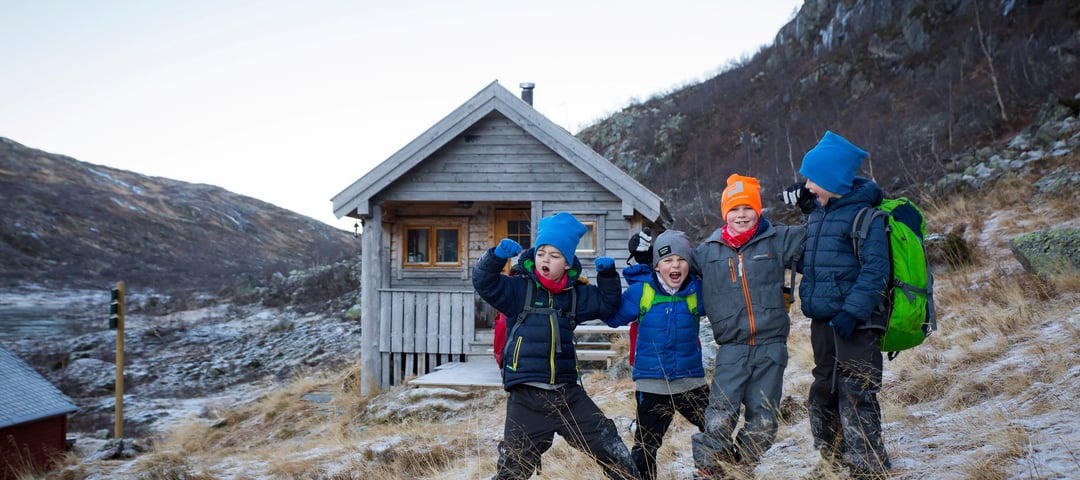 Fire barn tuller foran hytte i fjellet