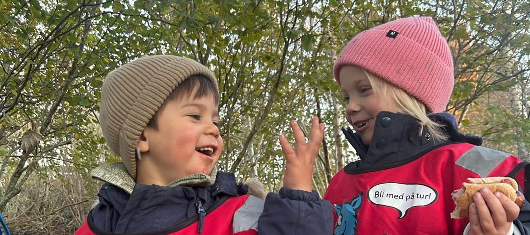 To barn i røde turbovester ler og koser seg i Turboklubb