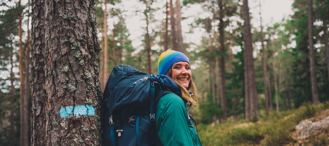 Kvinne med stor sekk i skogen