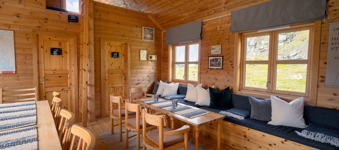 Interiør inne i den selvbetjente delen av Stranddalen. Sofa, stoler og bord som er flott dekorert med pynteputer.