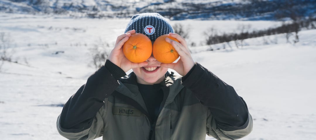Gutt som holder to appelsiner foran ansiktet