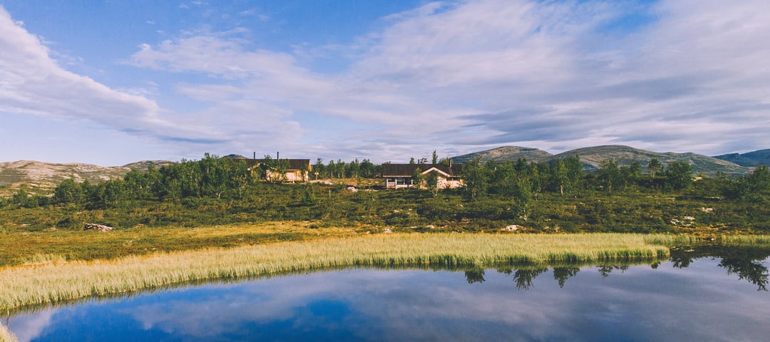 En innsjø med et hus og trær i bakgrunnen