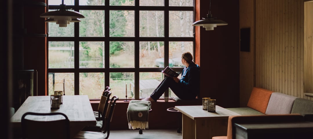 Person som sitter i vinduskarmen og ser ut på naturen.