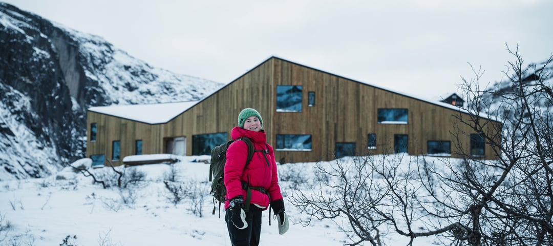 En jente med rød jakke står foran en helt ny hytte.