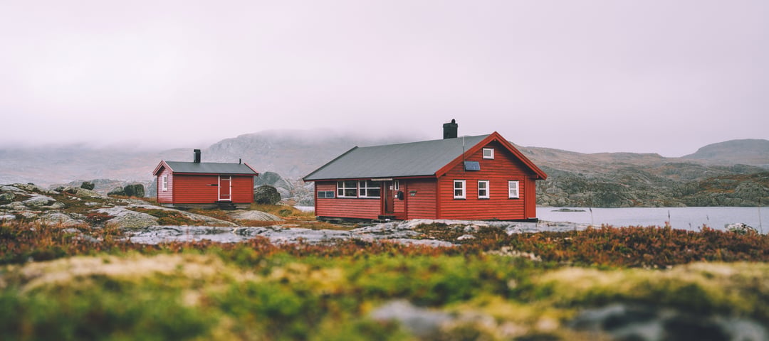 Krossvatn. 2 røde hytter . Den ene er litt mindre enn den andre. Det er grått vær. Typisk høst. 