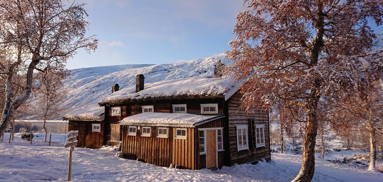 Tømmerhytte i snø.
