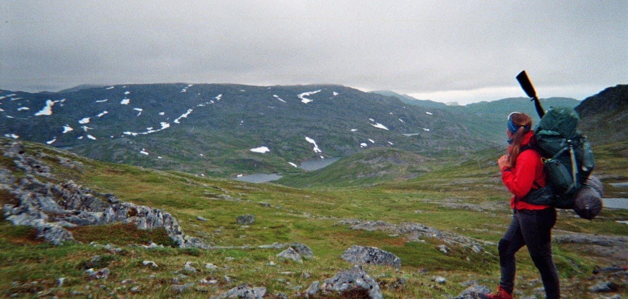 Jente med rød jakke og tursekk ser utover Sørøya
