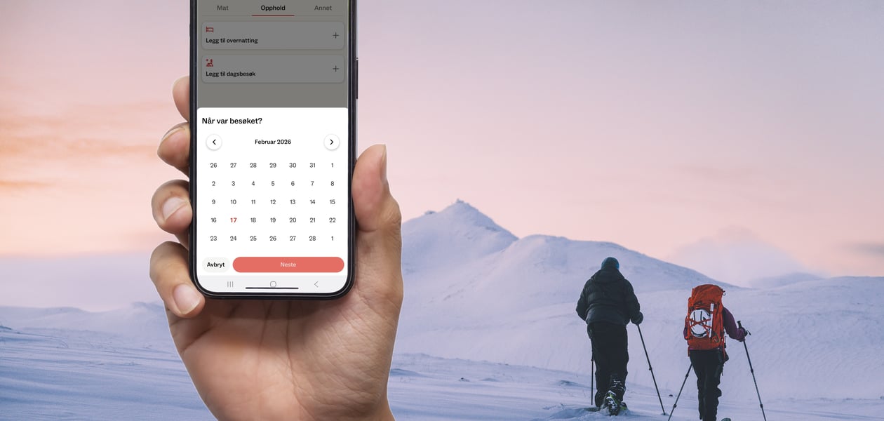 Hånd med mobil foran folk som går på ski i vinterlandskap
