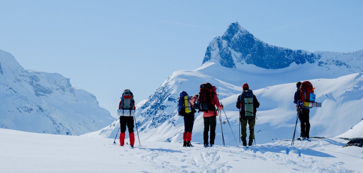 Flere personer med fjell som ser på en fjelltopp