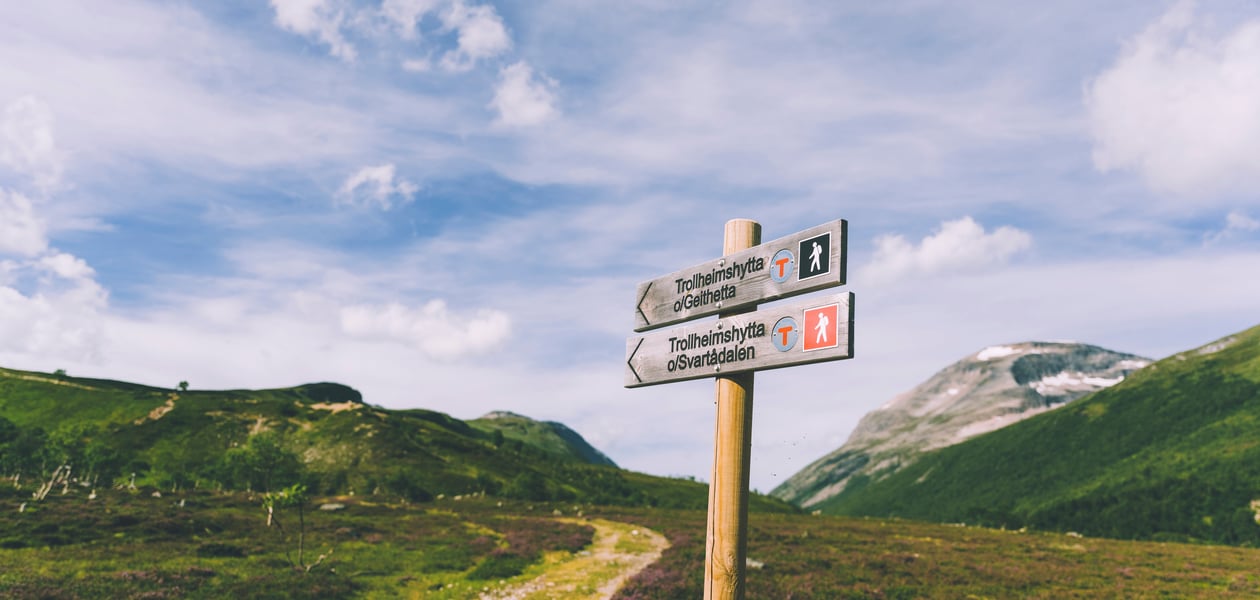 Skilt som viser mot en sti innover fjellet