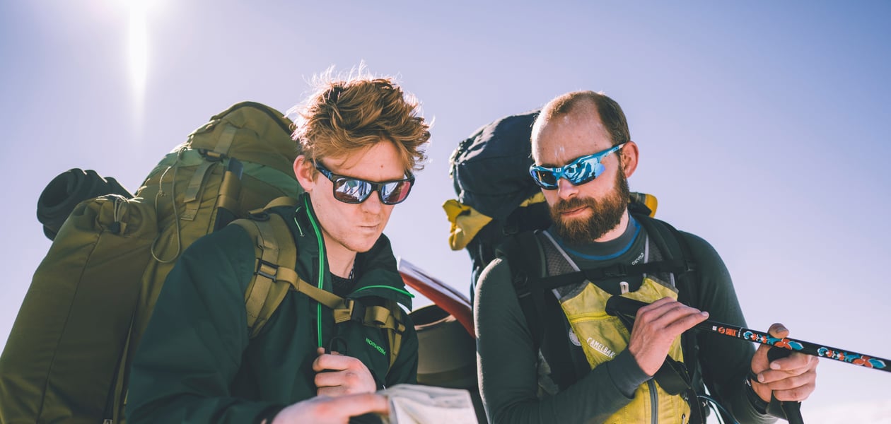 To menn med tursekk ser på kart