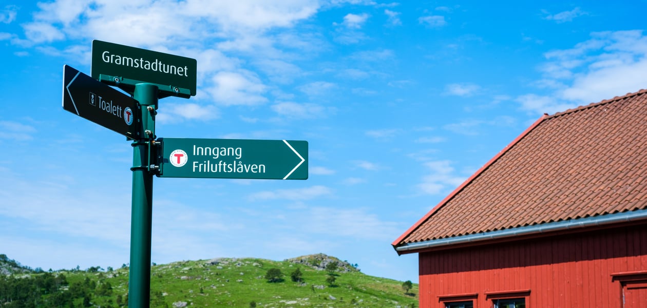 Nærbilde av grønne turskilt som er montert utenfor en rød låve.