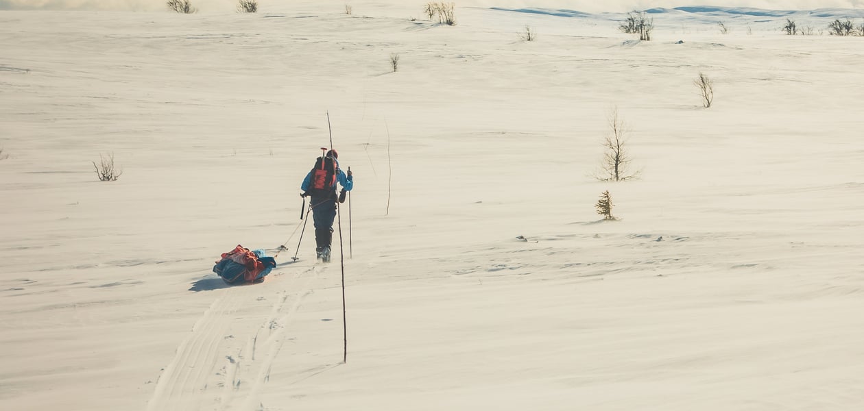 En person som går på ski med pulk i vinterfjellet