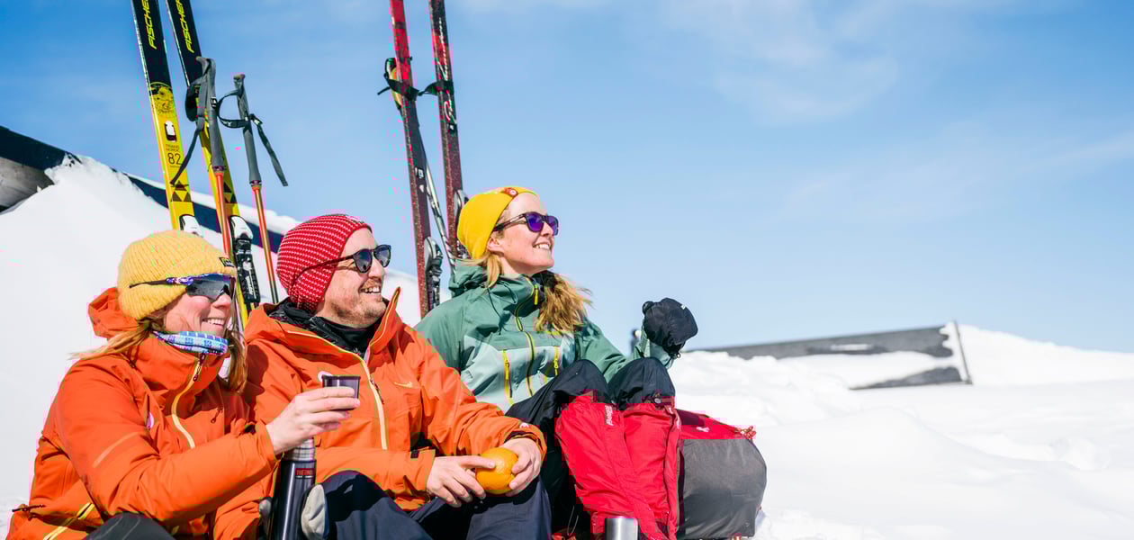 tre påsketurister i solveggen, koser seg med kaffe og appelsin