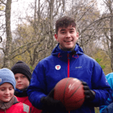 mann med ball og barn leker i skog