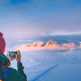 Person som tar bilde av vinterlandskap med telefon.