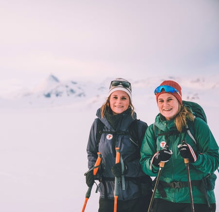 To smilende damer på ski på vinterfjellet. 