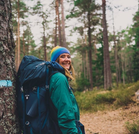 Kvinne med stor sekk i skogen