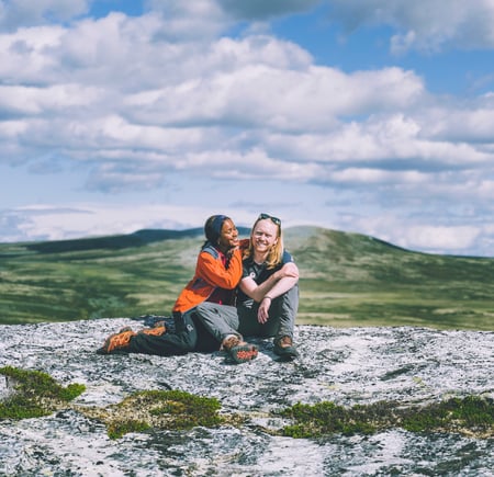 Par holder rundt hverandre på fjellknaus. 