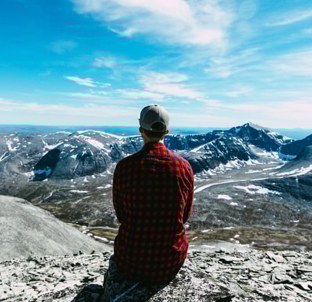 Person i rød skjorte som ser utover et fjellområde