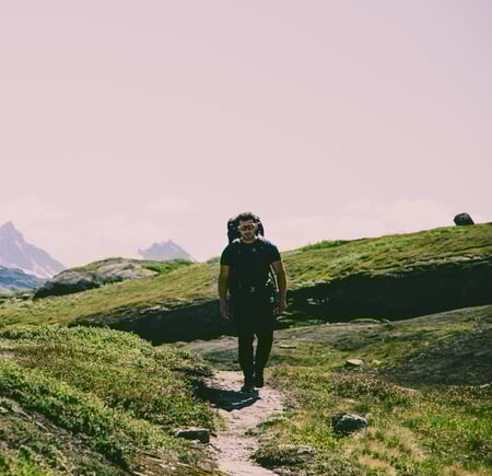 Mann som går tur på en sti i fjellet