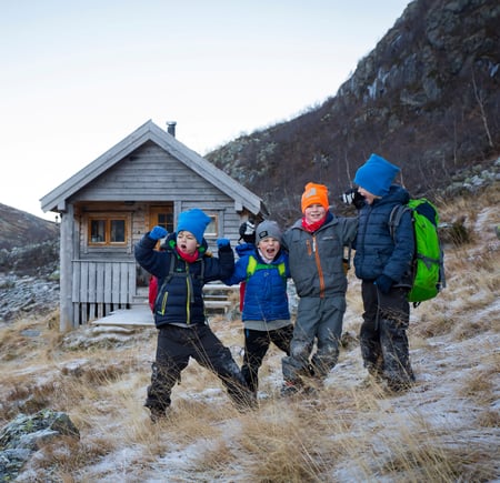 Fire barn tuller foran hytte i fjellet