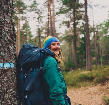Kvinne med stor sekk i skogen