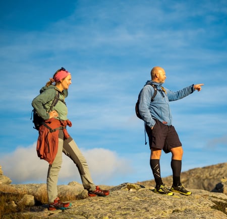 To personer står på et fjel og speider utover. Han ene peker