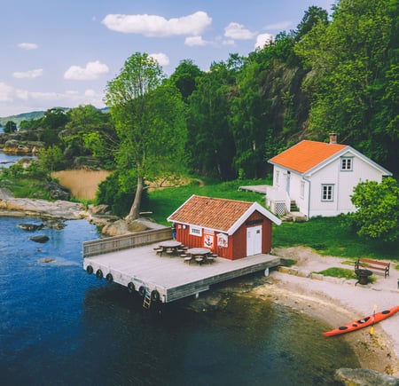 Hvit hytte med rødt anneks, ved hvit sandstrand