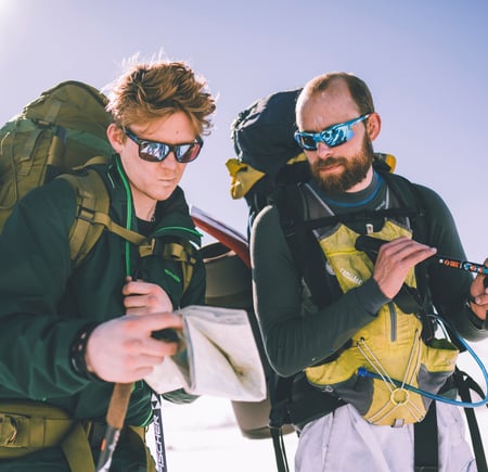 To menn med tursekk ser på kart