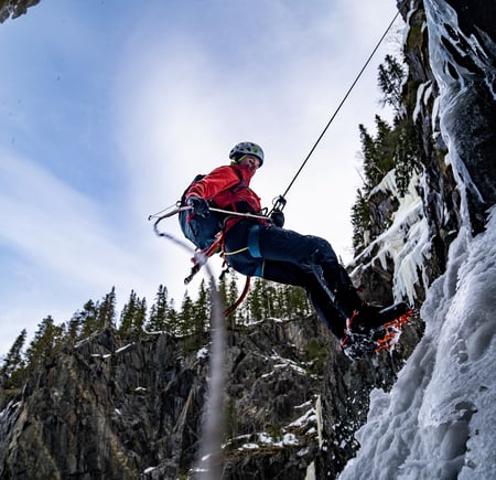 Isklatrer henger i tau ved frosset foss.