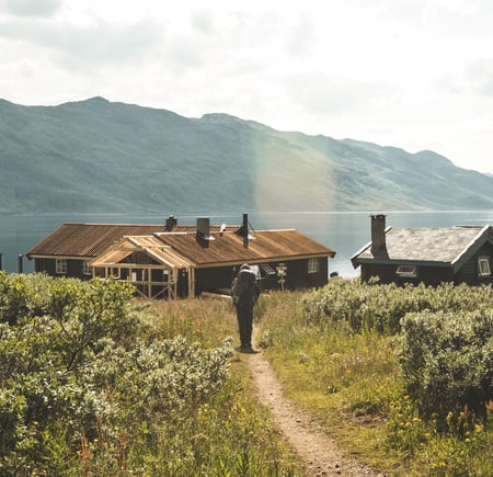 Person som går mot en hytte i fjellet