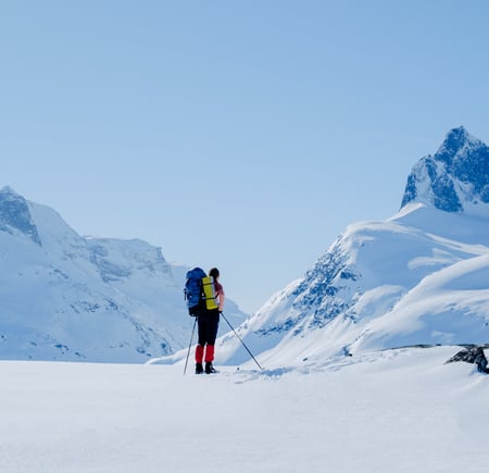 Dame som står på ski og ser på et fjell