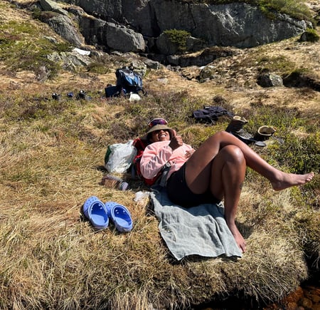 En dame ligger i gresset og soler seg.